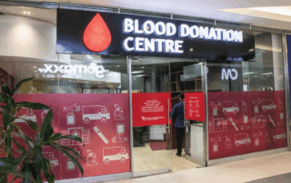 Blood Donation Centre storefront with a red drop logo and glass doors in a mall setting.